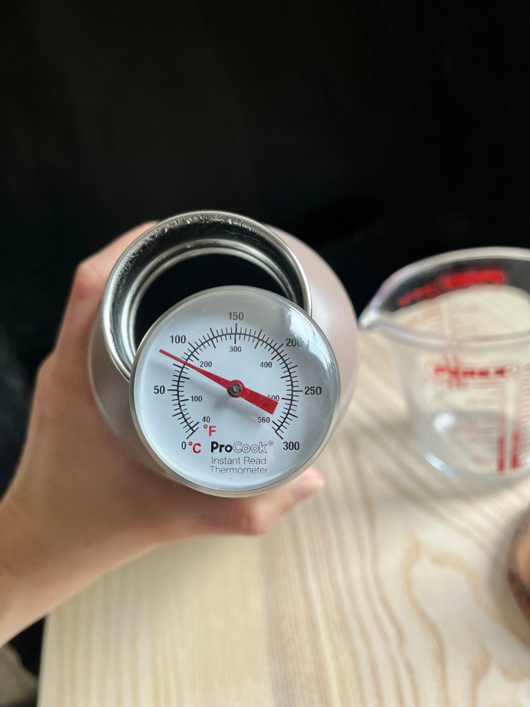 An instant read thermometer measuring 80 C sticking out of a thermos full of water