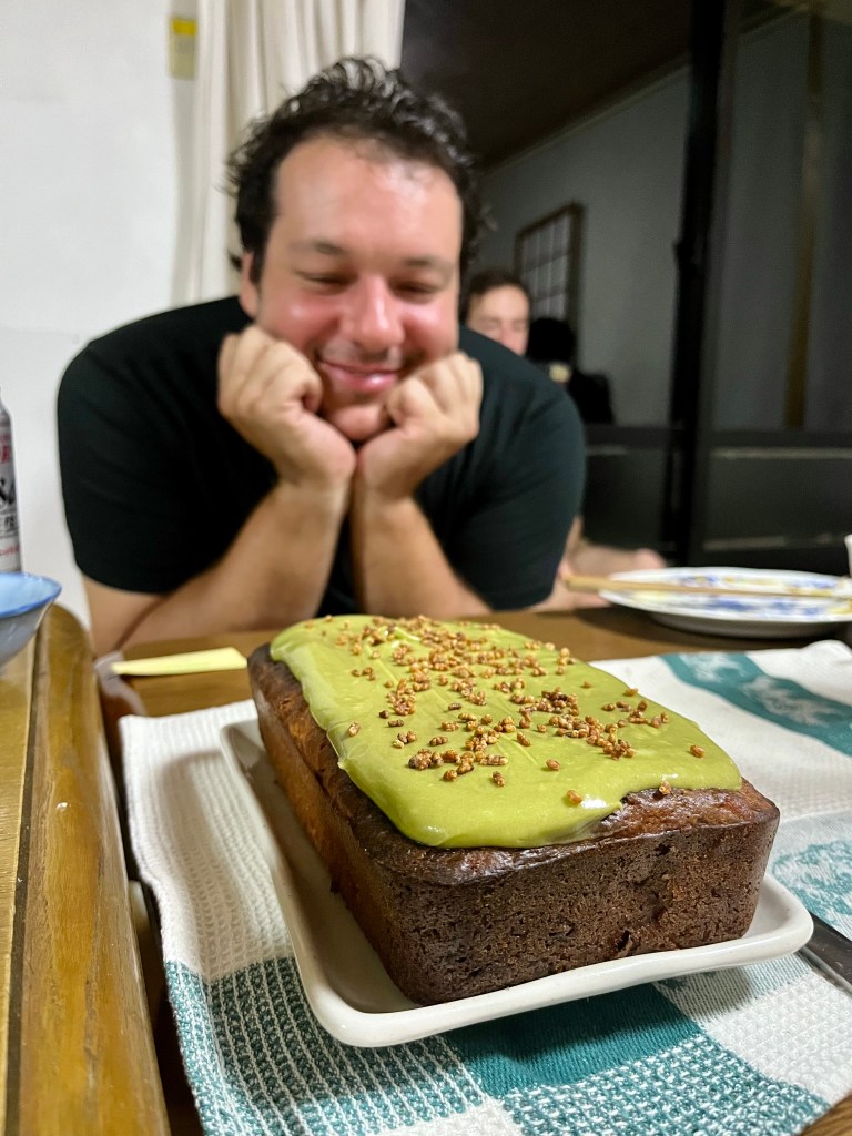 Carrot cake in loaf form in the foreground, with Julien staring lovingly at it in the background