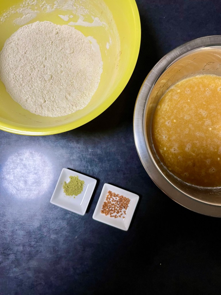 Dry ingredient mix in a yellow bowl and wet ingredient mix in a silver bowl, with trays of genmai and genmaicha powder